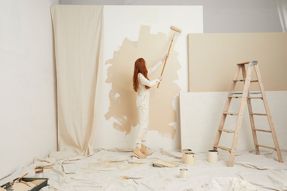 Woman in boots painting a wall