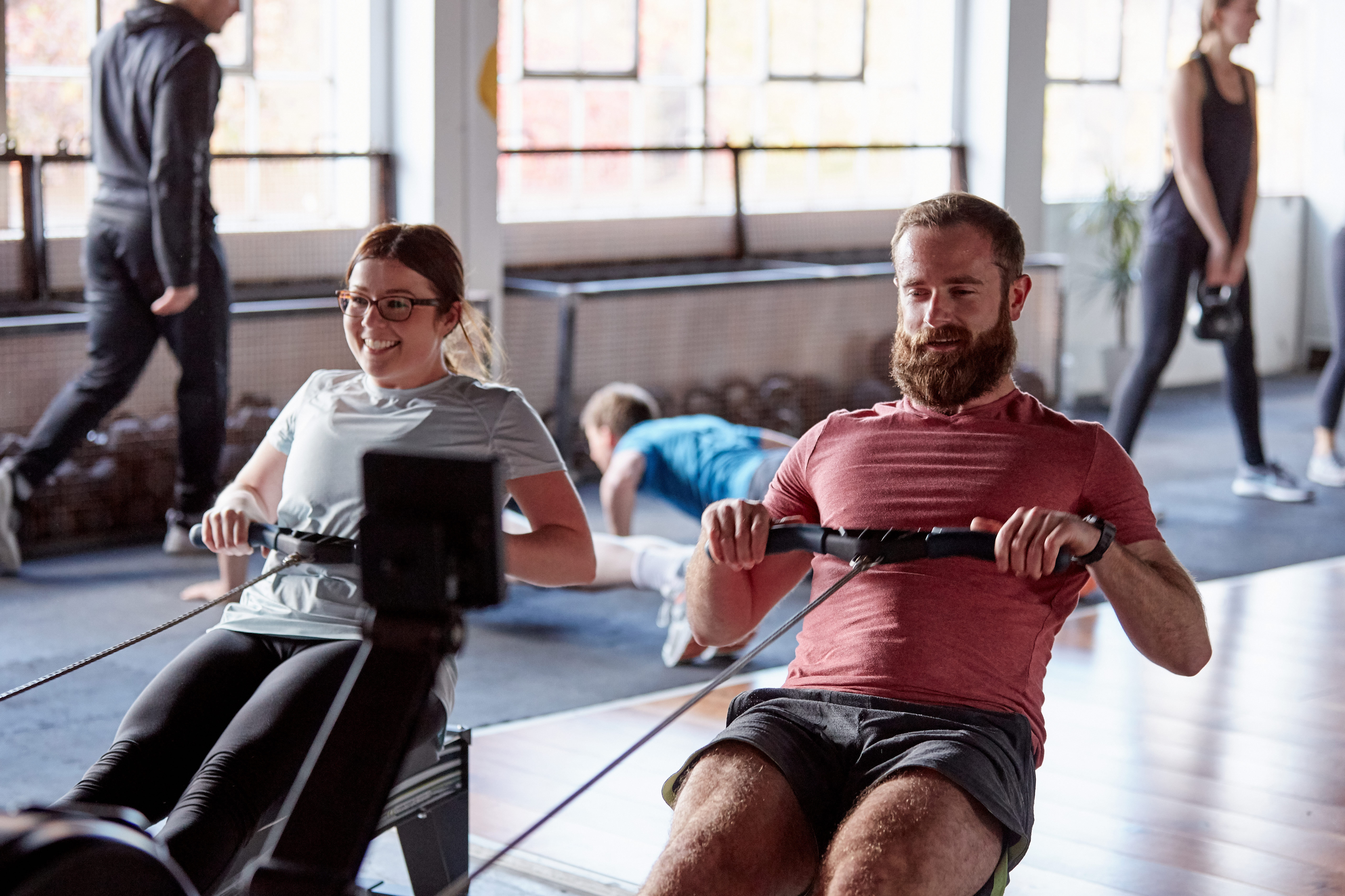 Man and woman using rowing simulators