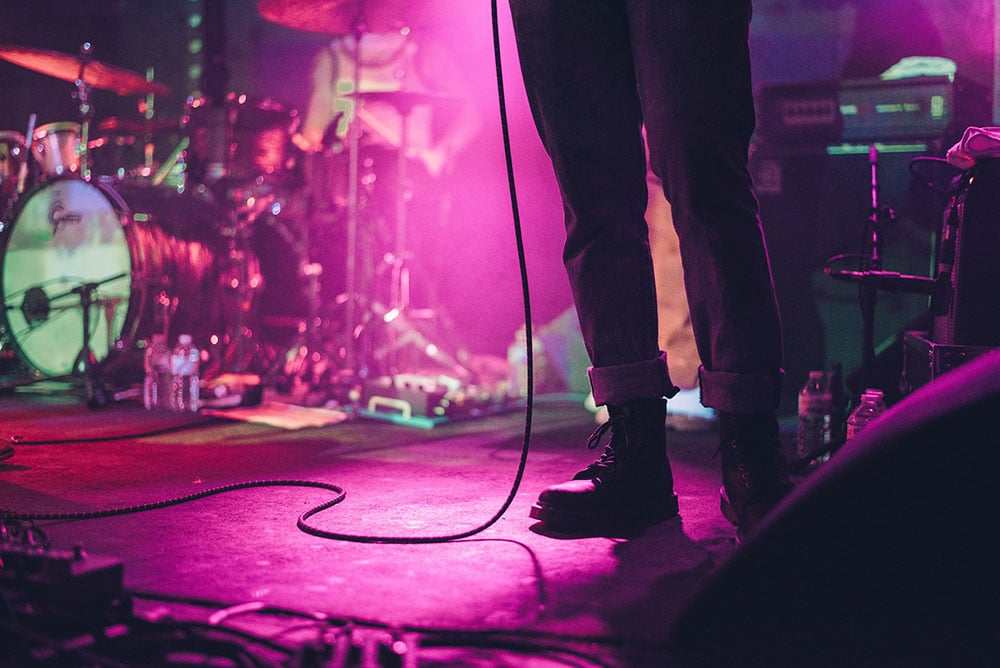 Feet of band members on stage with pink lighting