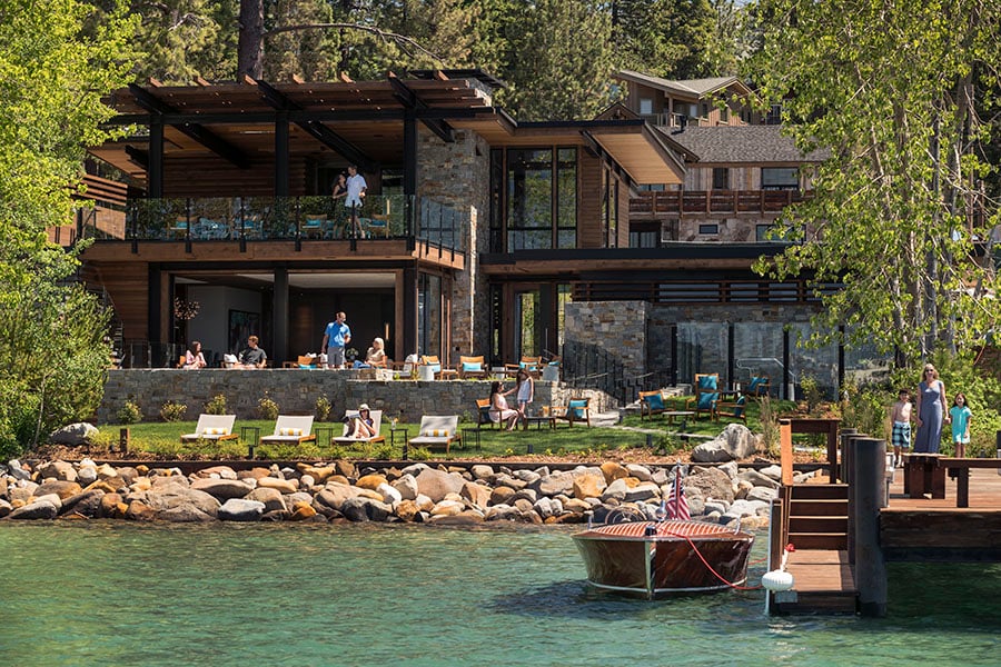 people at a lake house with a boat out front