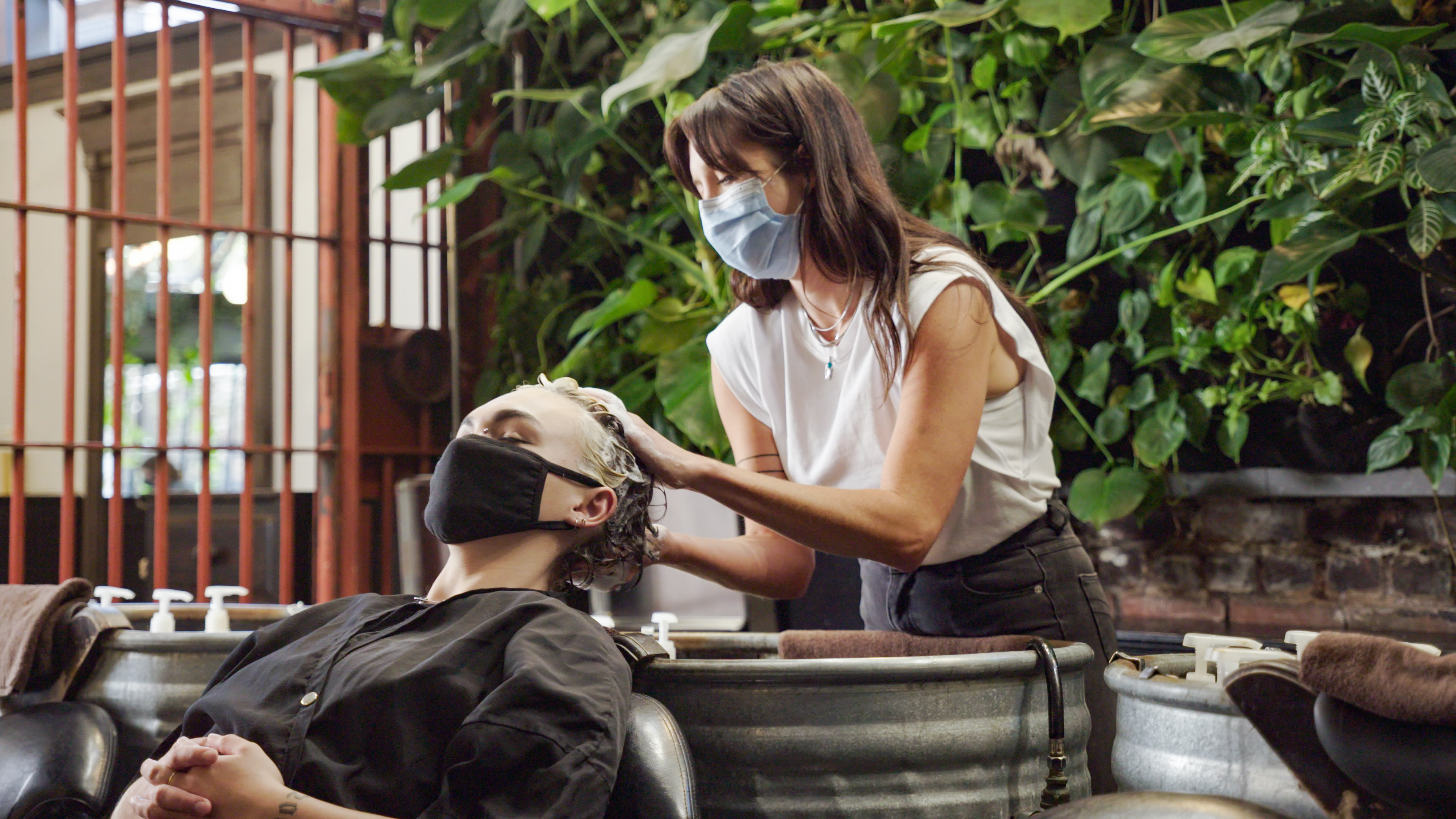 Stylist washing client's hair over a metal basin